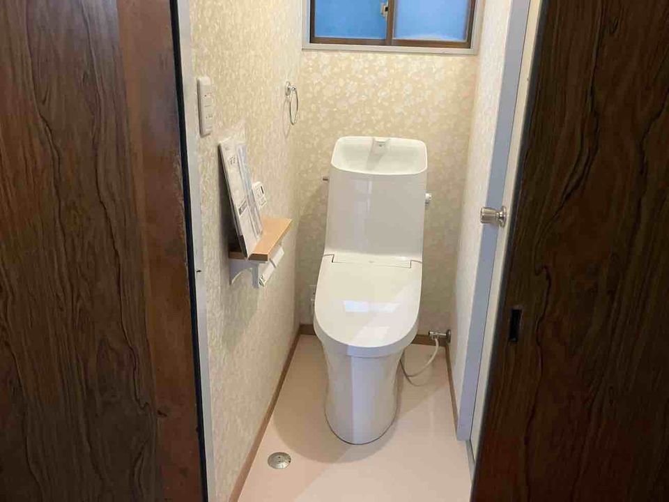 トイレ入口から見た便器、タンク上の手洗い、奥の窓と左側の紙巻器の参考写真